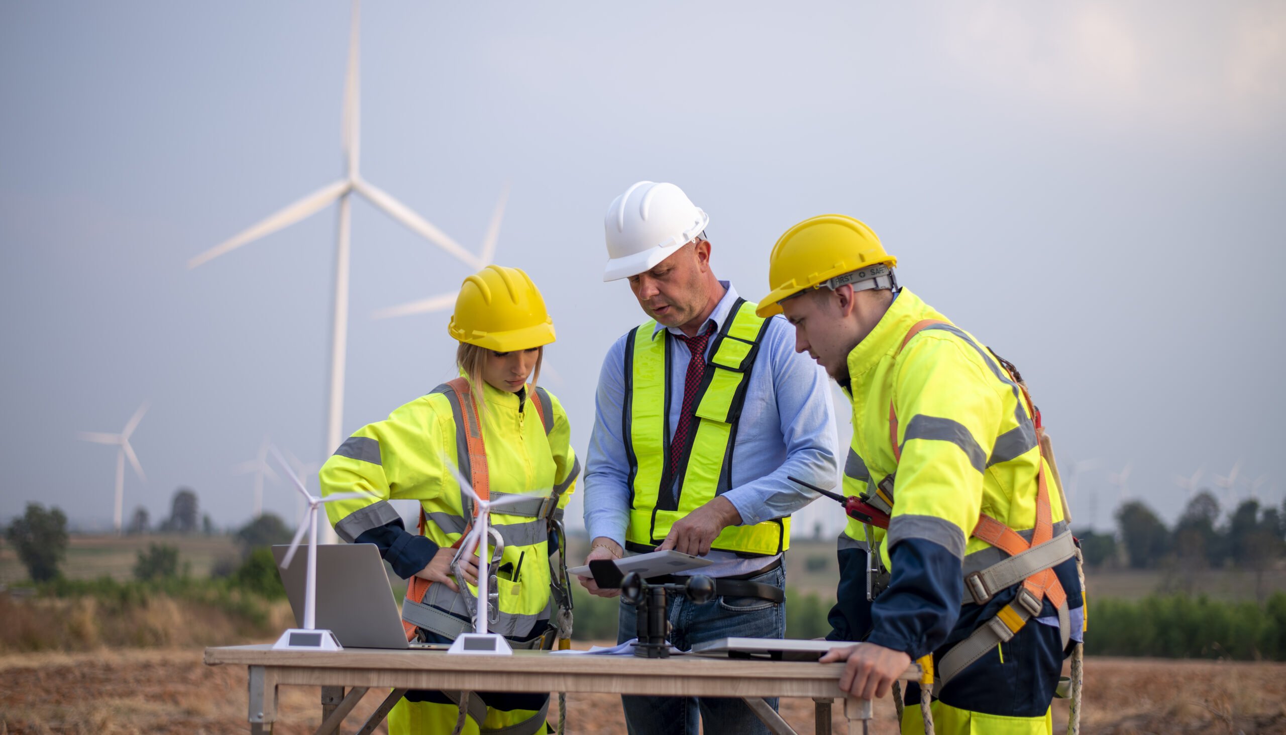 engenheiro topógrafo e gerente vestindo uniforme andando segurando inspeção de caixa e tablet trabalhando na rotação de fazendas de turbinas eólicas para eletricidade, energia renovável alternativa para o conceito de energia limpa